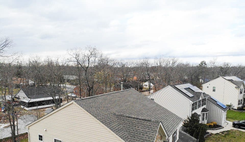 Aerial view of a finished gray shingle roof on a beige two-story house
